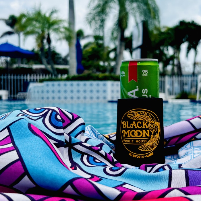 A Black Moon drink koozie on a can beside a pool