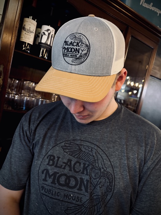 A man wearing a Black Moon trucker hat and t-shirt