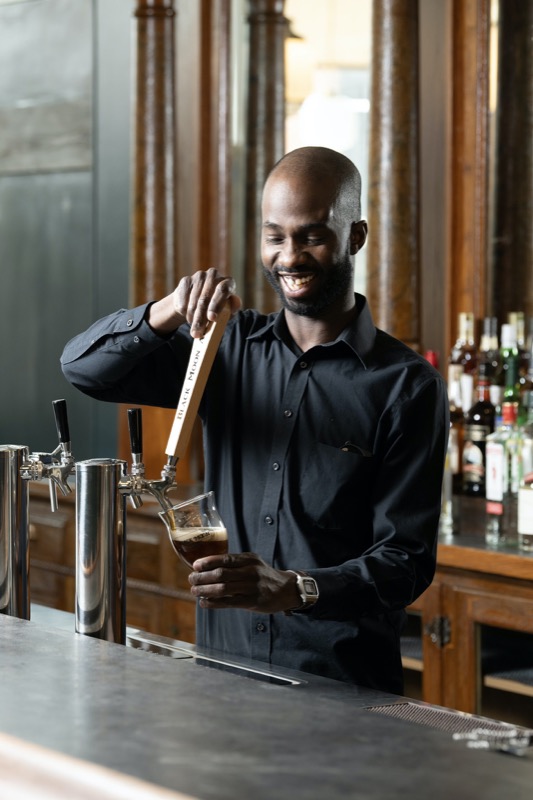 A smiling bartender pulling a draft beer